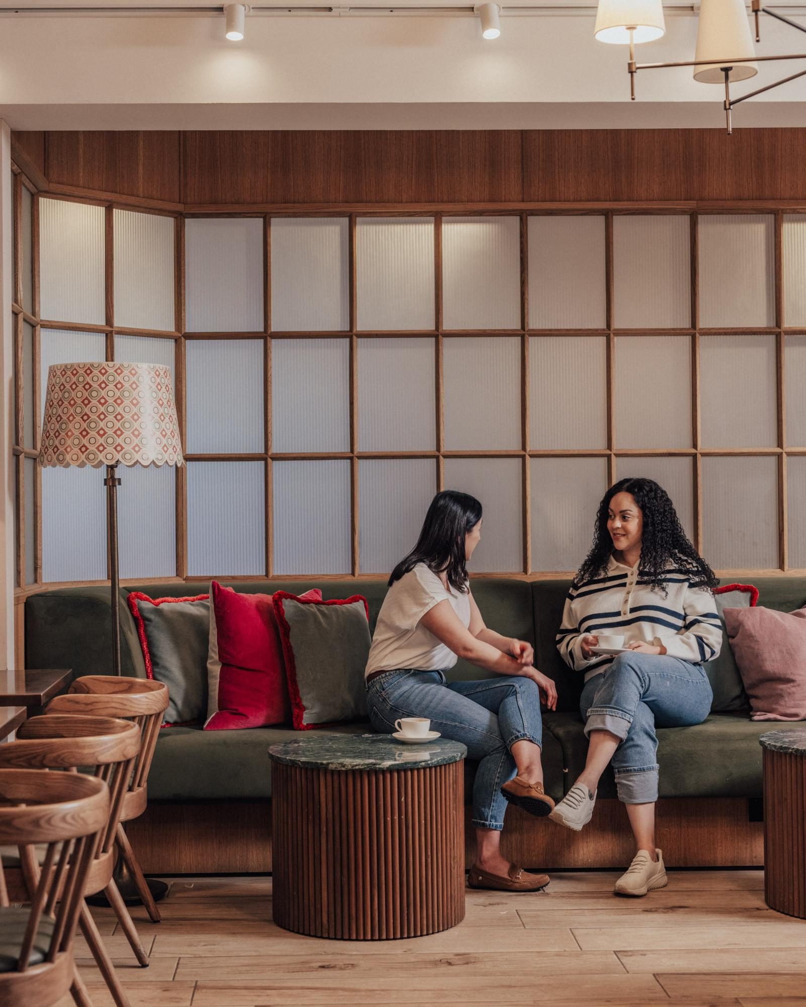 Two women chatting on a sofa in the café at Jesse’s House